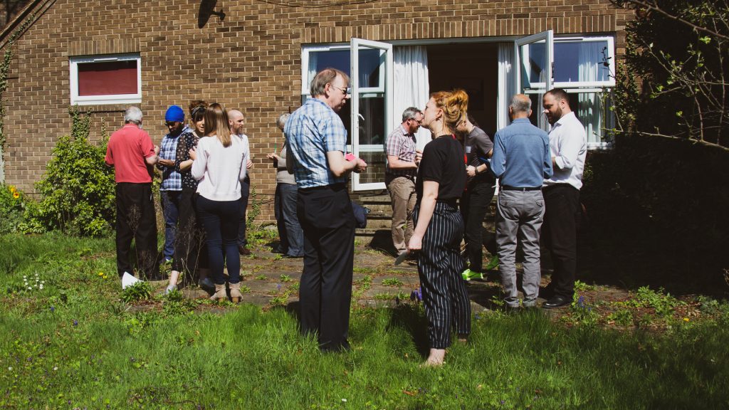 Building connections and networks is key to delivering social impact. 
Image of people assembled in a garden talking and making connections with one another.